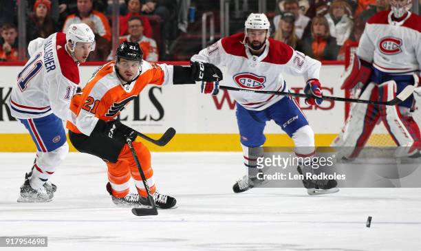 Scott Laughton of the Philadelphia Flyers skates after the loose puck against Brendan Gallagher and David Schlemko of the Montreal Canadiens on...