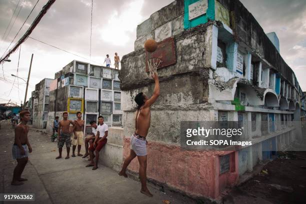 Locals seen playing basketball in a slum in a cemetery. In the center of Pasay District of Metro Manila is a cemetery where over 10,000 deceased...