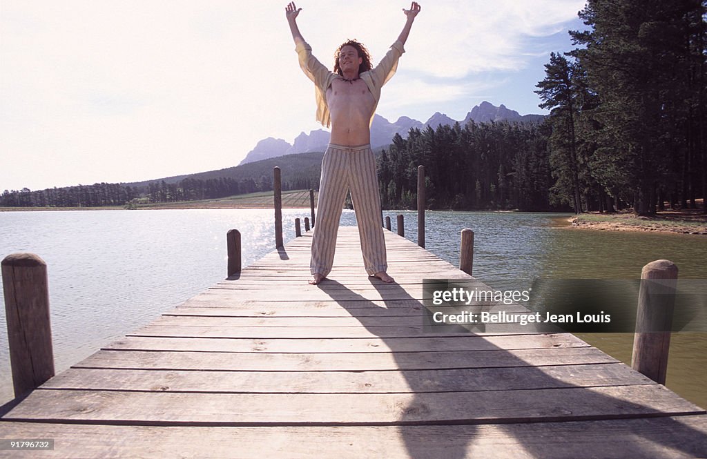 Man standing on dock with arms raised