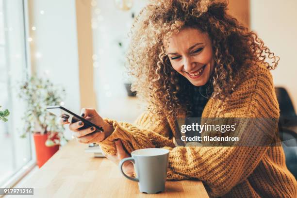 pretty woman texting on the phone - mid adult woman sweater stock pictures, royalty-free photos & images