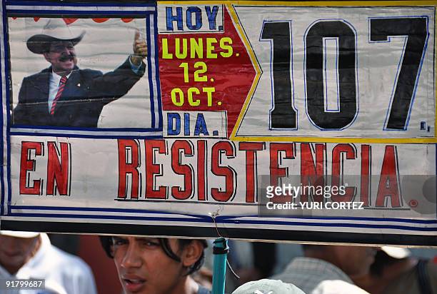 Supporter of deposed Honduran president Manuel Zelaya stands under an allusive signduring a protest at the Kenedy neighborhood in Tegucigalpa on...