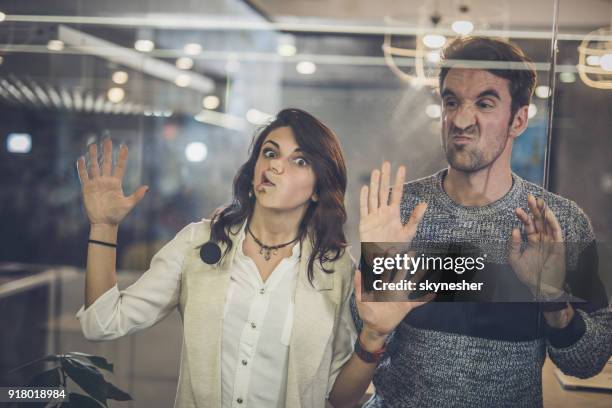 compañeros juguetones divertirse mientras que se pega sus rostros en la pared de cristal. - sticky fotografías e imágenes de stock