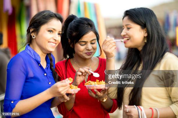 women eating snack at street market - street food stock pictures, royalty-free photos & images