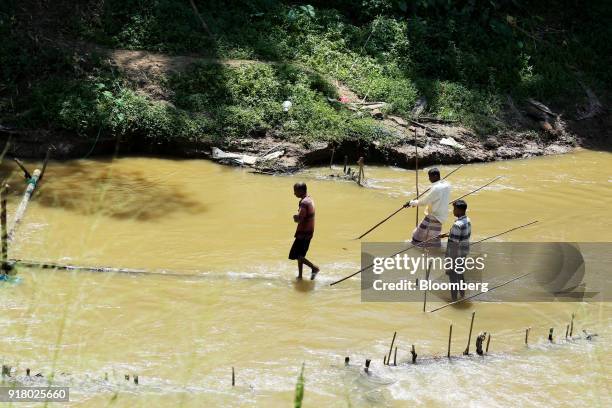 Gem miners use long wooden poles to cut up the riverbed in the Vhay river in Ratnapura District, Sabaragamuwa Province, Sri Lanka, on Wednesday, Feb....