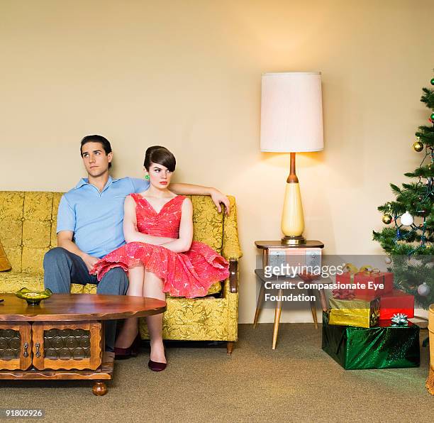 upset looking couple next to christmas tree - table romantique photos et images de collection