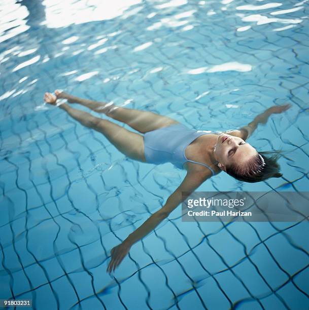 woman floating in pool - drijven stockfoto's en -beelden