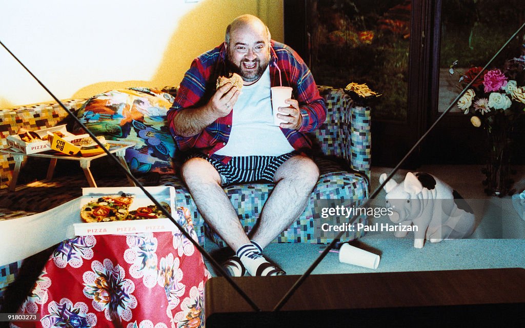 Man watching tv and eating junk food