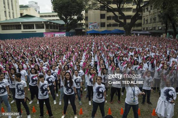 Students and teachers of St. Scholastica's College gesture the "number one" sign as they dance to take part in the "One Billion Rising" global...