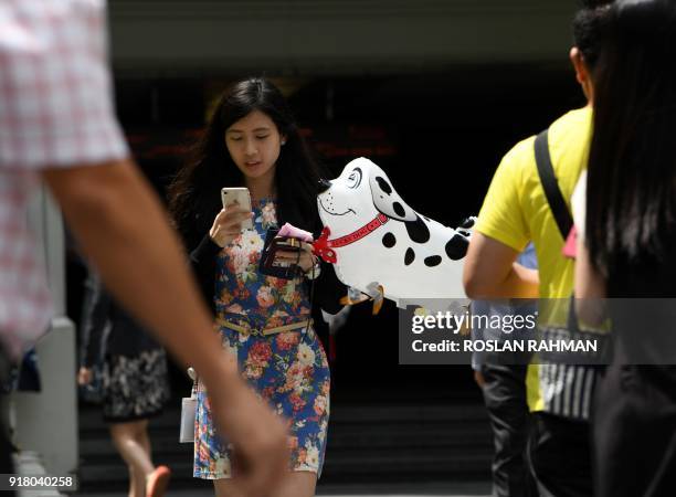 Woman walks with a balloon in the shape of a dog during lunch time at the financial business district in Singapore on February 14 ahead of the Lunar...