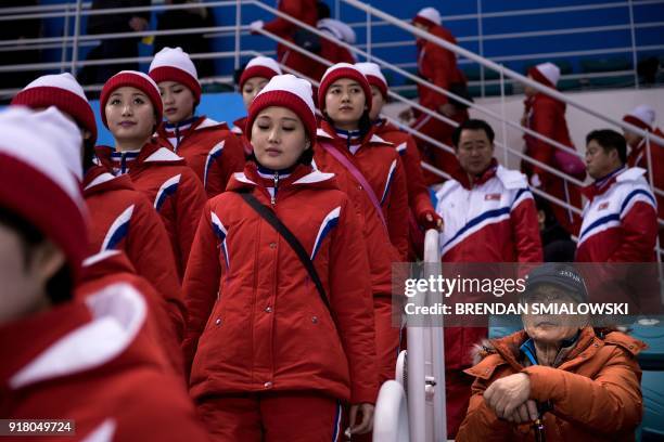 Fan of team Japan sits while North Korean cheerleaders arrive for a women's preliminary round ice hockey match between Unified Korea and Japan during...