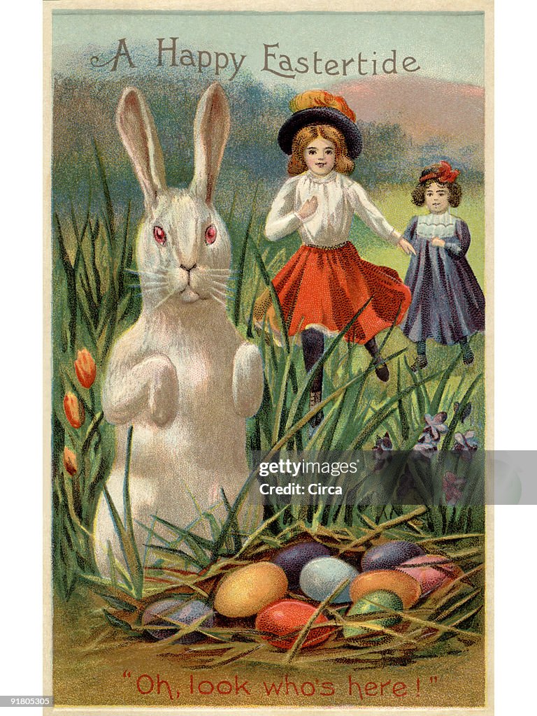A vintage Easter postcard of two girls running towards a rabbit and a nest of colored eggs
