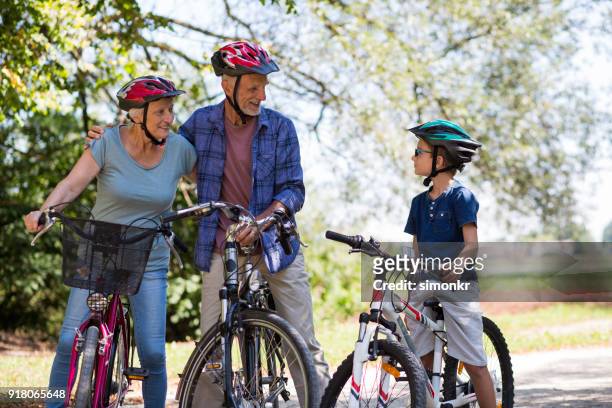 familjen ridning cykel i park - öppna och stäng knapp bildbanksfoton och bilder