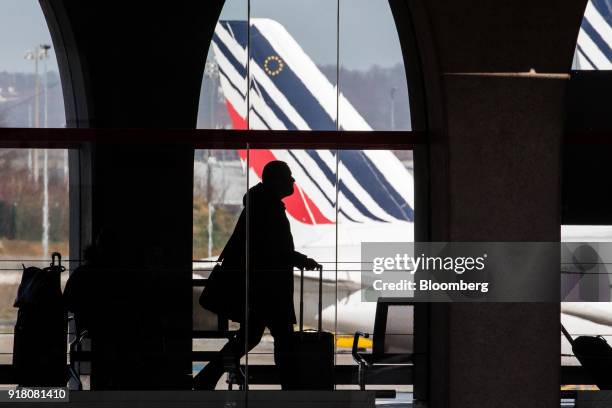 Passenger walks through the terminal as Tricolour livery sits on the tail fin of an Air France passenger aircraft beyond, operated by Air France-KLM...