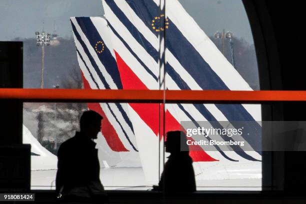 Passengers walk through the terminal as Tricolour livery sits on the tail fin of an Air France passenger aircraft beyond, operated by Air France-KLM...