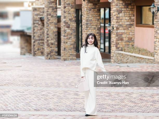 trendy woman wearing white turtleneck and white trousers on the street - street fashion asian stock pictures, royalty-free photos & images