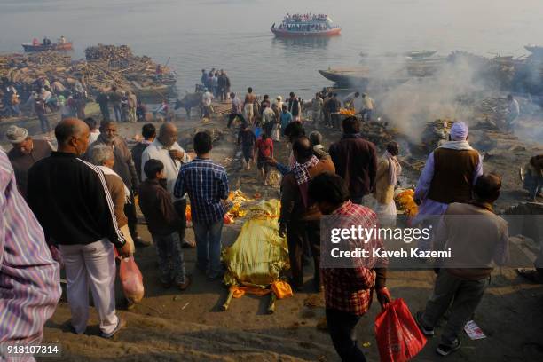 Relatives of deceased men wait on the staircase of Manikarnika Ghat to dip the bodies in Ganges River for a final purification act before the...