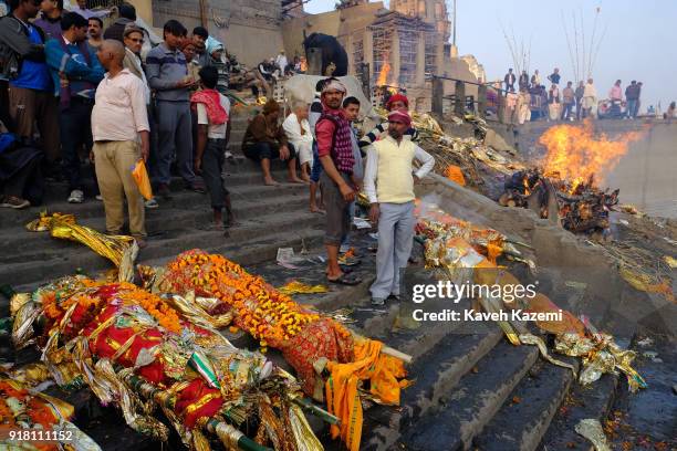 Relatives of deceased men wait on the staircase of Manikarnika Ghat to dip the bodies in Ganga River for a final purification act before the...
