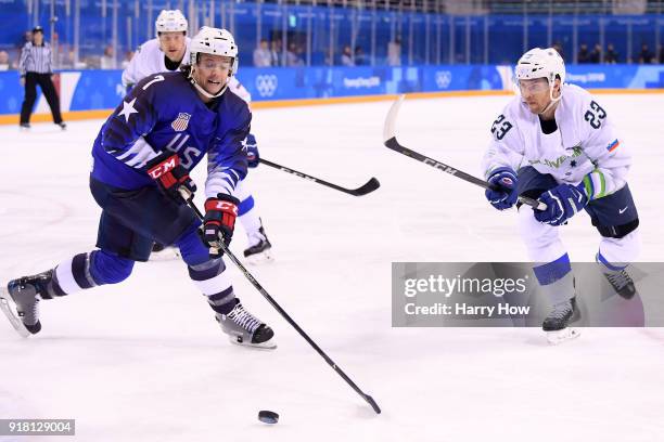 John McCarthy of the United States controls the puck against Luka Vidmar of Slovenia during the Men's Ice Hockey Preliminary Round Group B game on...