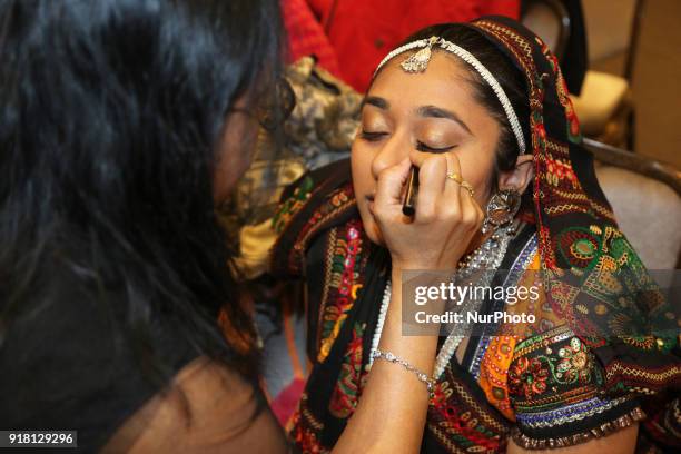 Make-up artist applies makeup to Indian girls representing the state of Rajasthan during a traditional Indian folk dance competition held in...