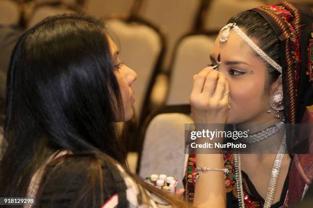 Make-up artist applies makeup to Indian girls representing the state of Rajasthan during a traditional Indian folk dance competition held in...