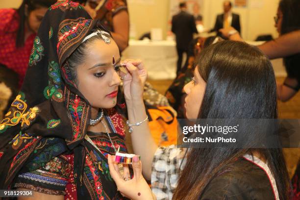 Make-up artists apply makeup to Indian girls representing the state of Rajasthan during a traditional Indian folk dance competition held in...