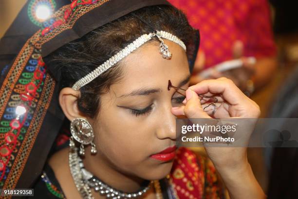 Make-up artist applies makeup to Indian girls representing the state of Rajasthan during a traditional Indian folk dance competition held in...