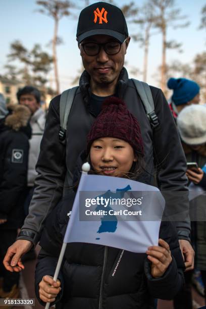 Girl holds a unified Korean flag as she queues to watch the Women's Ice Hockey Preliminary Round Group B game between Korea and Japan on day five of...
