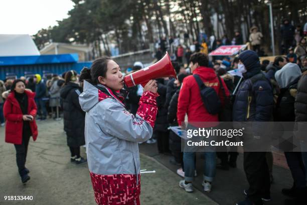 Volunteer makes an announcement through a loudspeaker to people queuing to watch the Women's Ice Hockey Preliminary Round Group B game between Korea...