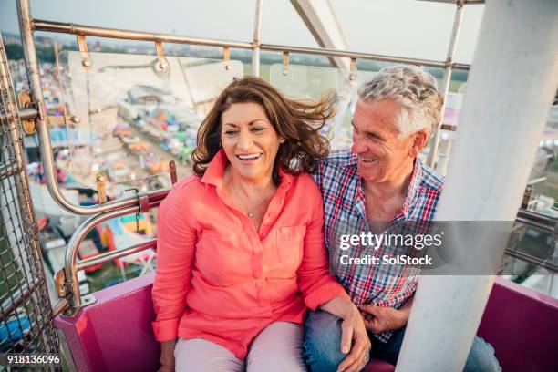 activo pareja senior en el parque de atracciones - noria fotografías e imágenes de stock