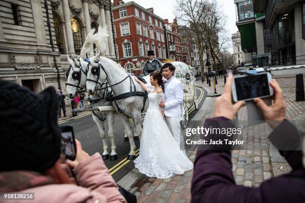 Couple pose for wedding pictures with white horses and a carriage in Westminster on Valentine's Day on January 29, 2018 in London, England.