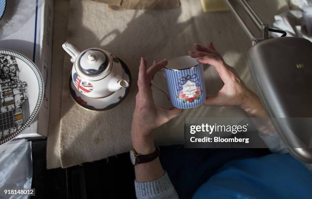 An employee checks a china mug made to commemorate the wedding between Henry Windsor and Meghan Markle at Halcyon Days Ltd.'s factory in...