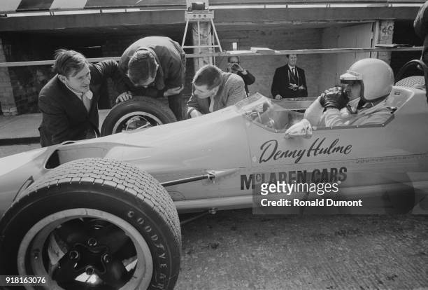 New Zealand racing driver Denny Hulme receives engine attention from McLaren team owner Bruce McLaren , Silverstone, UK, 5th April 1968.