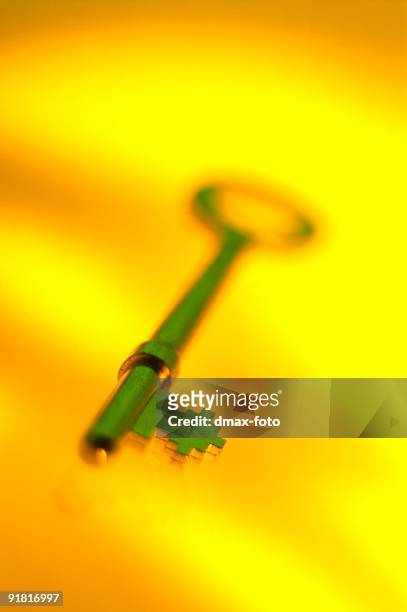 green colored key photographed against yellow background - fotohandy stock pictures, royalty-free photos & images