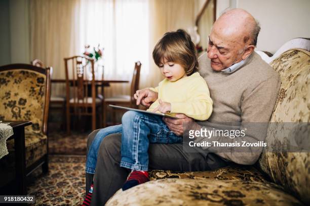 grandfather and his grandson using a digital tablet - grandfather stock pictures, royalty-free photos & images