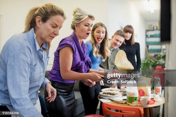 flipping pancakes in the office - shrovetide stock pictures, royalty-free photos & images