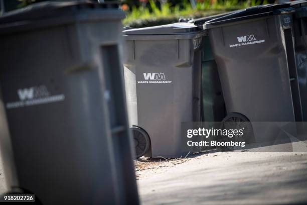 Trash bins displaying Waste Management Inc. Signage sit on a sidewalk in Hayward, California, U.S., on Monday, Feb. 12, 2018. Waste Management Inc....