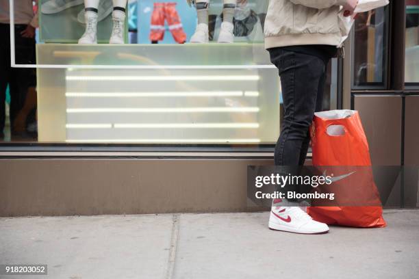 Shopper stands next to a Nike Inc. Retail bag on the sidewalk in the SoHo neighborhood of New York, U.S., on Friday, Feb. 9, 2018. Bloomberg is...