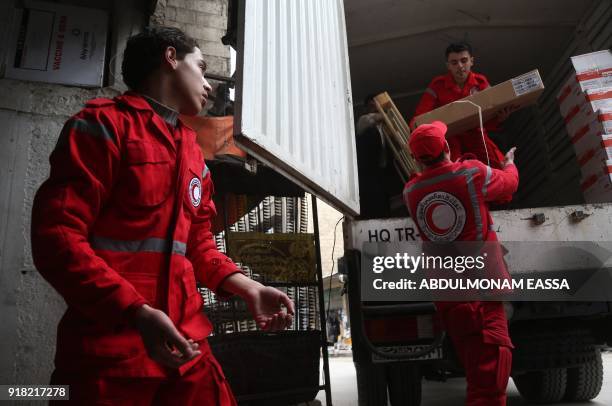 Syrian Arab Red Crescent volunteers offload aid from a lorry after an aid convoy arrived in the town of Douma, in the Syrian rebel enclave of Eastern...