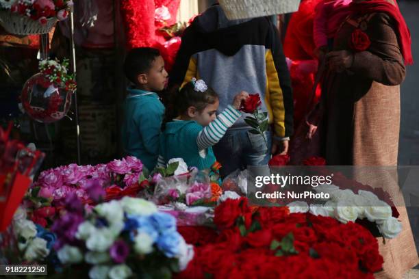 Palestinians walk past a shop selling red teddy bears, red balloons and pillows on Valentine's day in Gaza city on February 14, 2018.