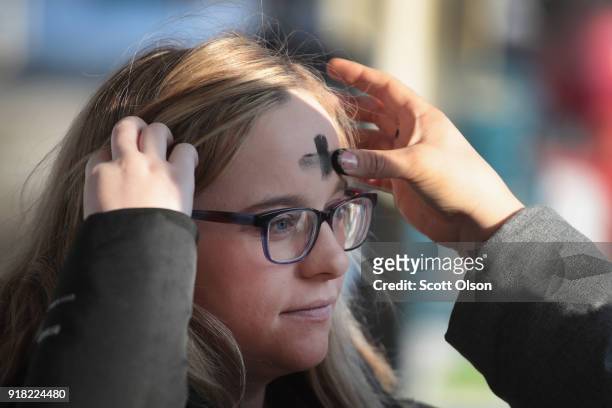Commuter has ashes applied to her forehead in celebration of Ash Wednesday before catching a subway train in the Logan Square neighborhood on...