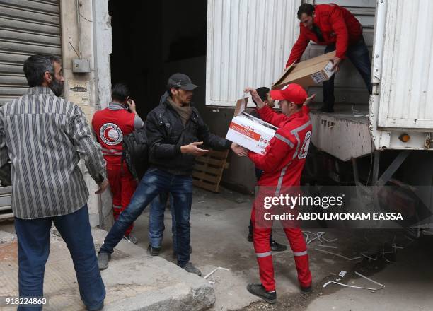 Syrian Arab Red Crescent volunteers and citizens offload aid from a lorry after an aid convoy arrived in Douma, in the Syrian rebel enclave of...