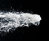 a jet of foam from a bottle of champagne on a black background. festive image