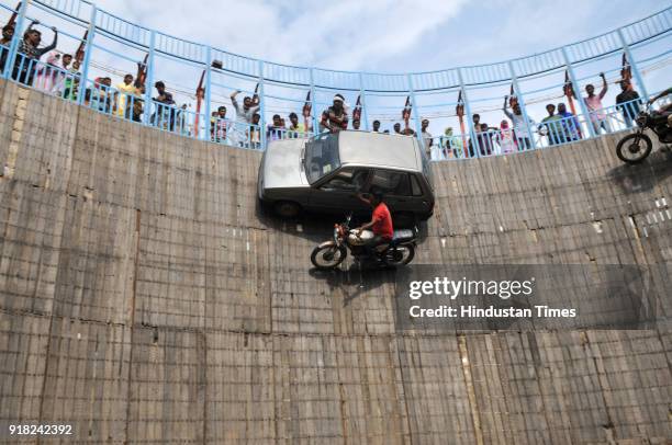 Stuntmen, Mustakeem 30, Saleem 27 and Aarif 28 drive their bikes and hang out of the window of cars as they steer them in front of the crowd at an...