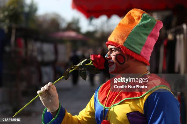 Palestinian clown presents roses and balloons to people in front of a shop on Valentine's day in Gaza city on February 14, 2018. Valentine's Day is...