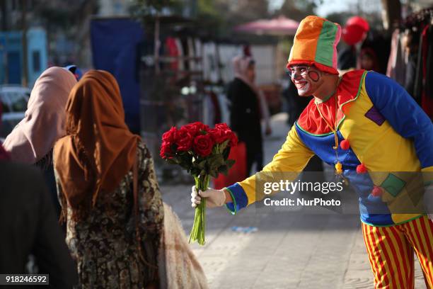 Palestinian clown presents roses and balloons to people in front of a shop on Valentine's day in Gaza city on February 14, 2018. Valentine's Day is...