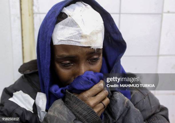 Bandaged African migrant cries after receiving medical treatment while sitting in a hospital, after their vehicle was overturned during a truck...