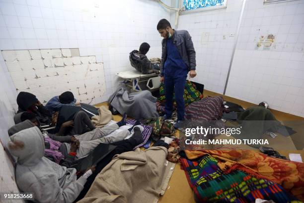 Libyan medical orderly checks on African migrants who were injured after their vehicle was overturned during a truck collision, in a hospital room in...