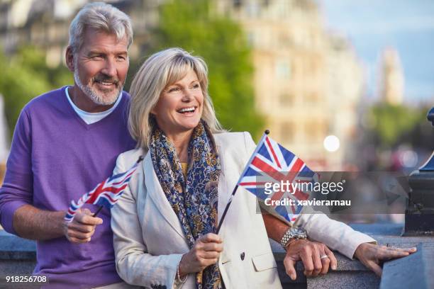 glimlachend senior paar staande met britse vlaggen - old uk flag stockfoto's en -beelden