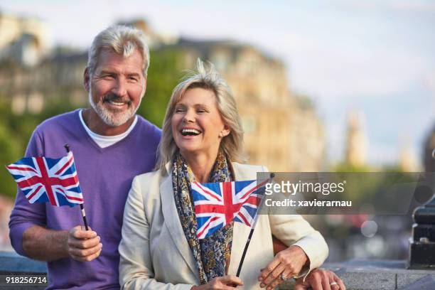 glimlachend senior paar staande met britse vlaggen - old uk flag stockfoto's en -beelden