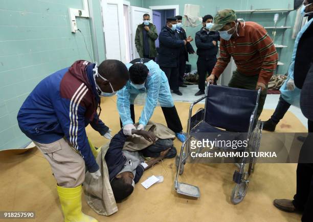 Libyan medical orderlies assist an African migrant lying on the floor, upon arriving at a hospital in the town of Beni Walid, 170 kilometres...